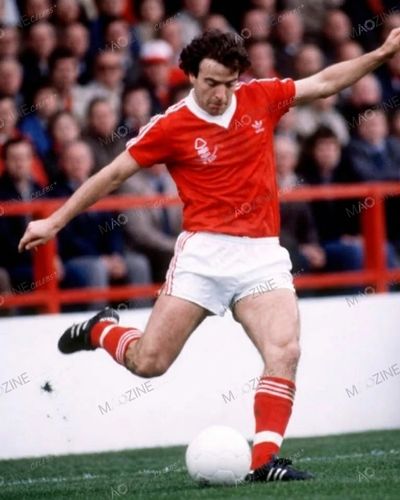John Robertson playing for Nottingham Forest in the classic red Adidas kit, crossing the ball with his left foot.