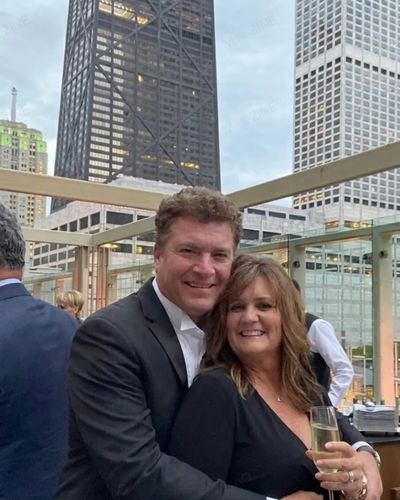 Pat Finn smiling with his wife Donna Crowley at a rooftop event in Chicago with skyline background.