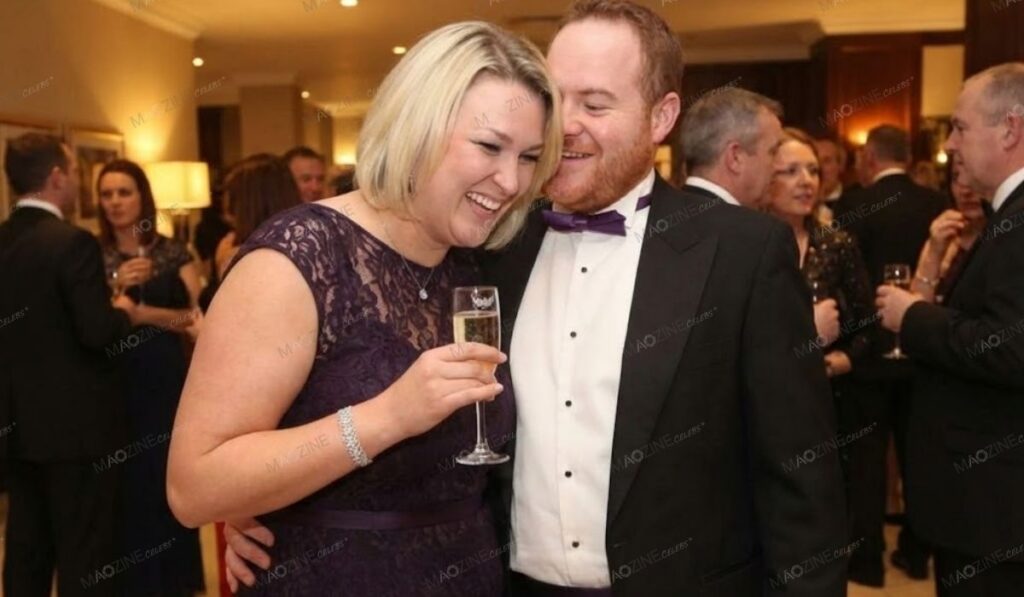 Sara Davies laughing with her husband Simon Davies wearing a tuxedo at a formal event.