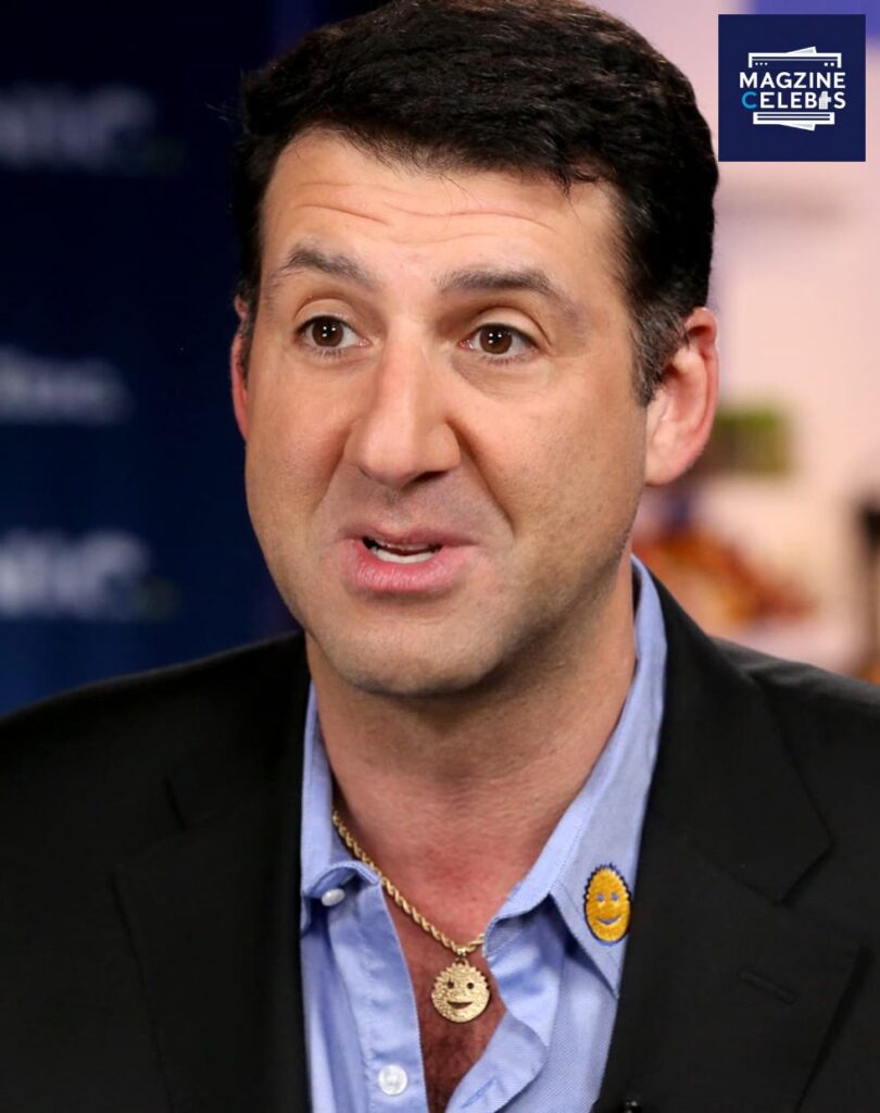 Scrub Daddy founder Aaron Krause smiling in a close-up portrait wearing his signature sponge pendant, 2025