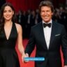 Ana de Armas and Tom Cruise holding hands on the red carpet at a Hollywood premiere, smiling in elegant evening outfits.