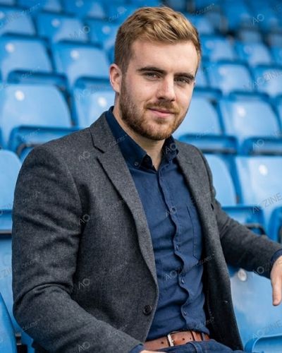 Portrait of Finlo Clarkson sitting in stadium seats, representing his passion for rugby and sports.