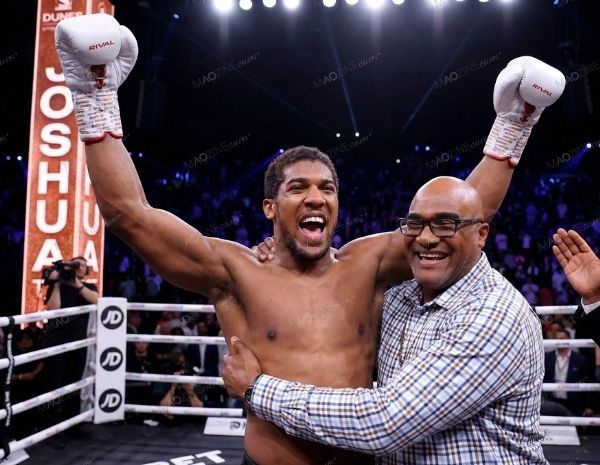 Anthony Joshua celebrating with his father Robert Joshua, both raising hands in joy inside the ring.