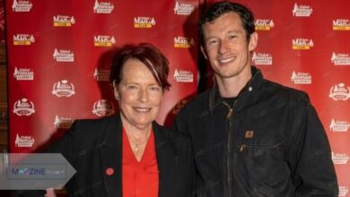 Rosemary Turner posing with her son, British actor Callum Turner, at the Global Woman Summit event. She is wearing a black blazer and red top, while Callum is in a casual black jacket.