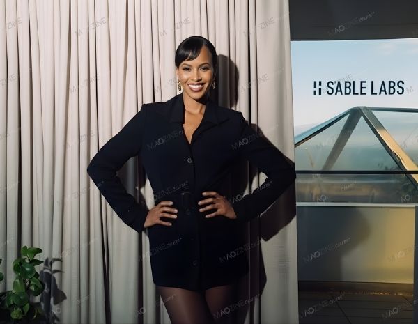 Sabrina Dhowre Elba smiling in a black blazer dress standing next to S'able Labs logo.