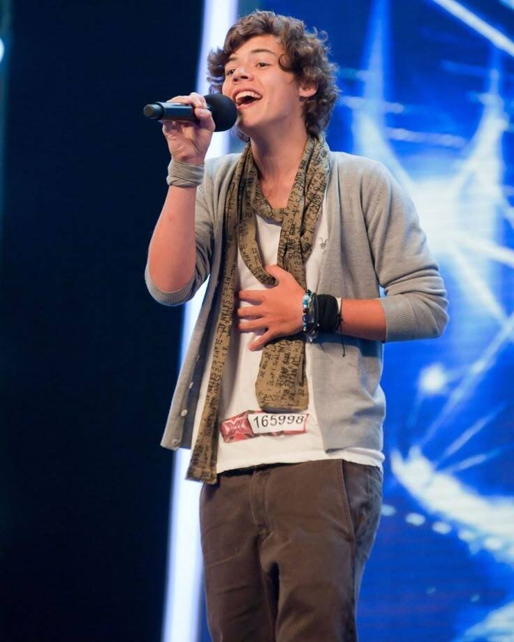 Harry Styles on X factor. He is holding a mic in his hand.