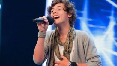 Harry Styles on X factor. He is holding a mic in his hand.